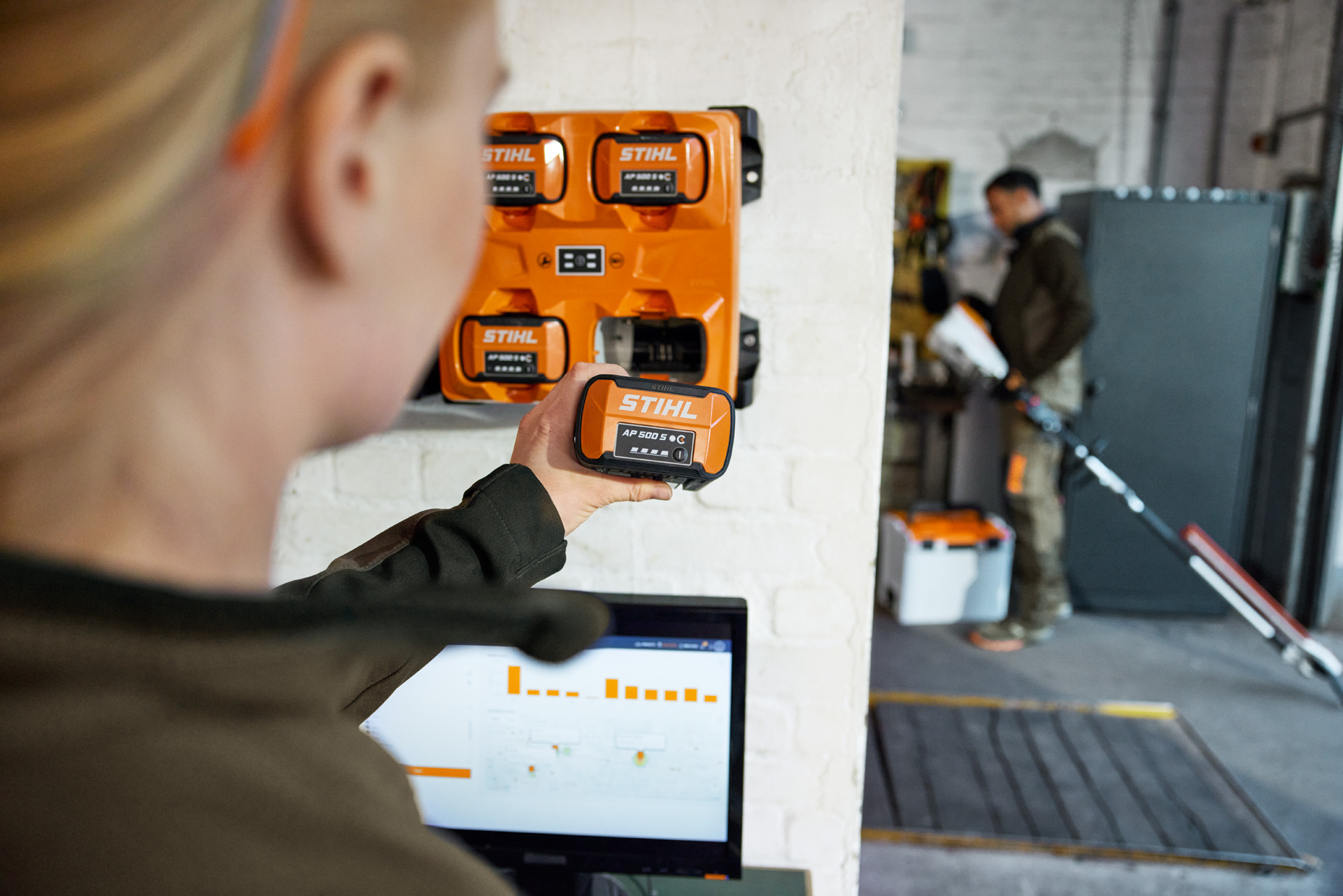 A woman in front of a laptop taking an AP 300 S from the STIHL AL 301-4 multi-charger